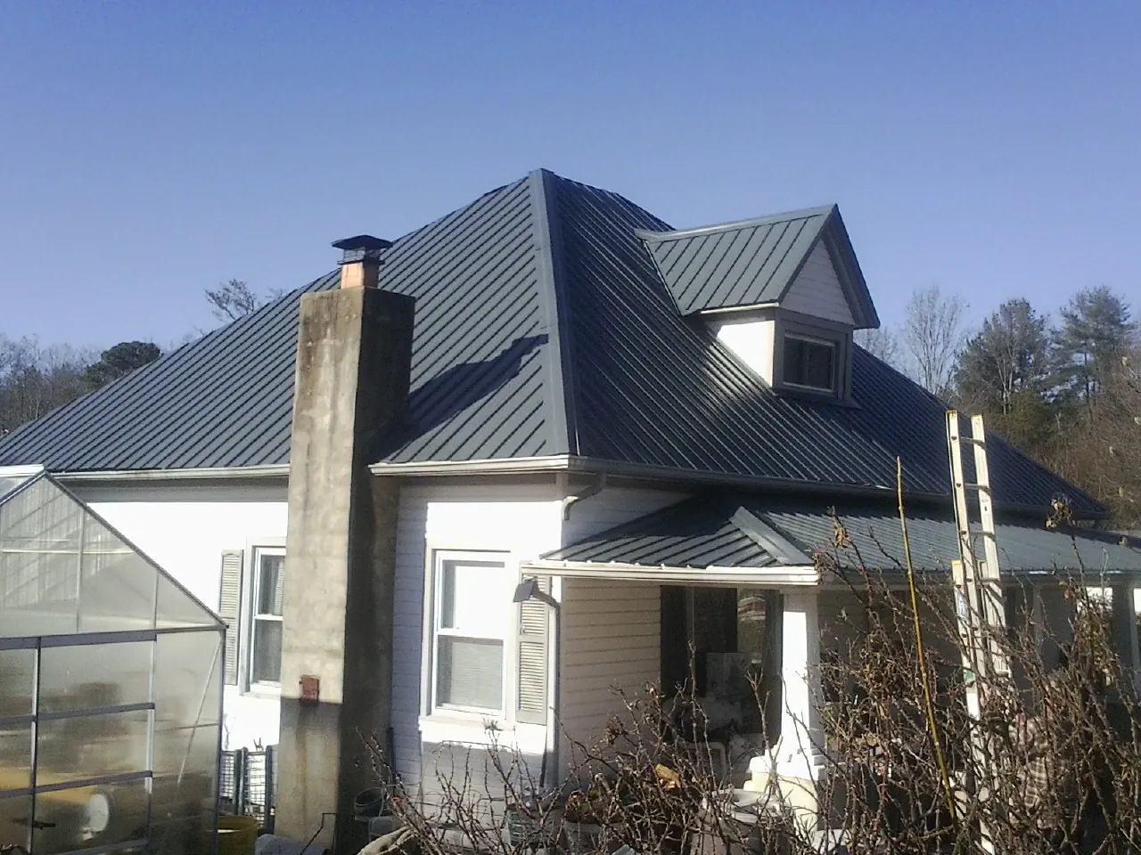 Dark blue standing seam metal roof on a white farmhouse with dormer — Slate & Tile Roof Repair by Roofing Brothers in Hamilton City