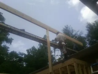 Carpenter setting a ridge beam over a new addition frame — Ice Dam Removal by Roofing Brothers in Hamilton City