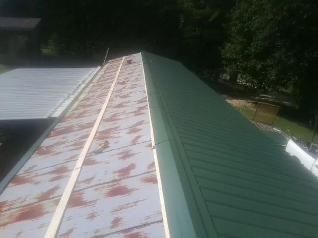 Old rusted panels beside newly installed green metal roofing — Wind Damage Roof Repair by Roofing Brothers in Hamilton City