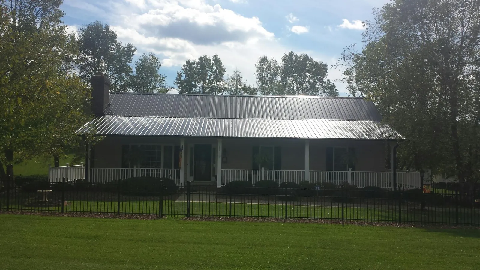 Gray metal roof on a brick ranch with a full width front porch — Gutter Guard Installation work by our crew in Hamilton City