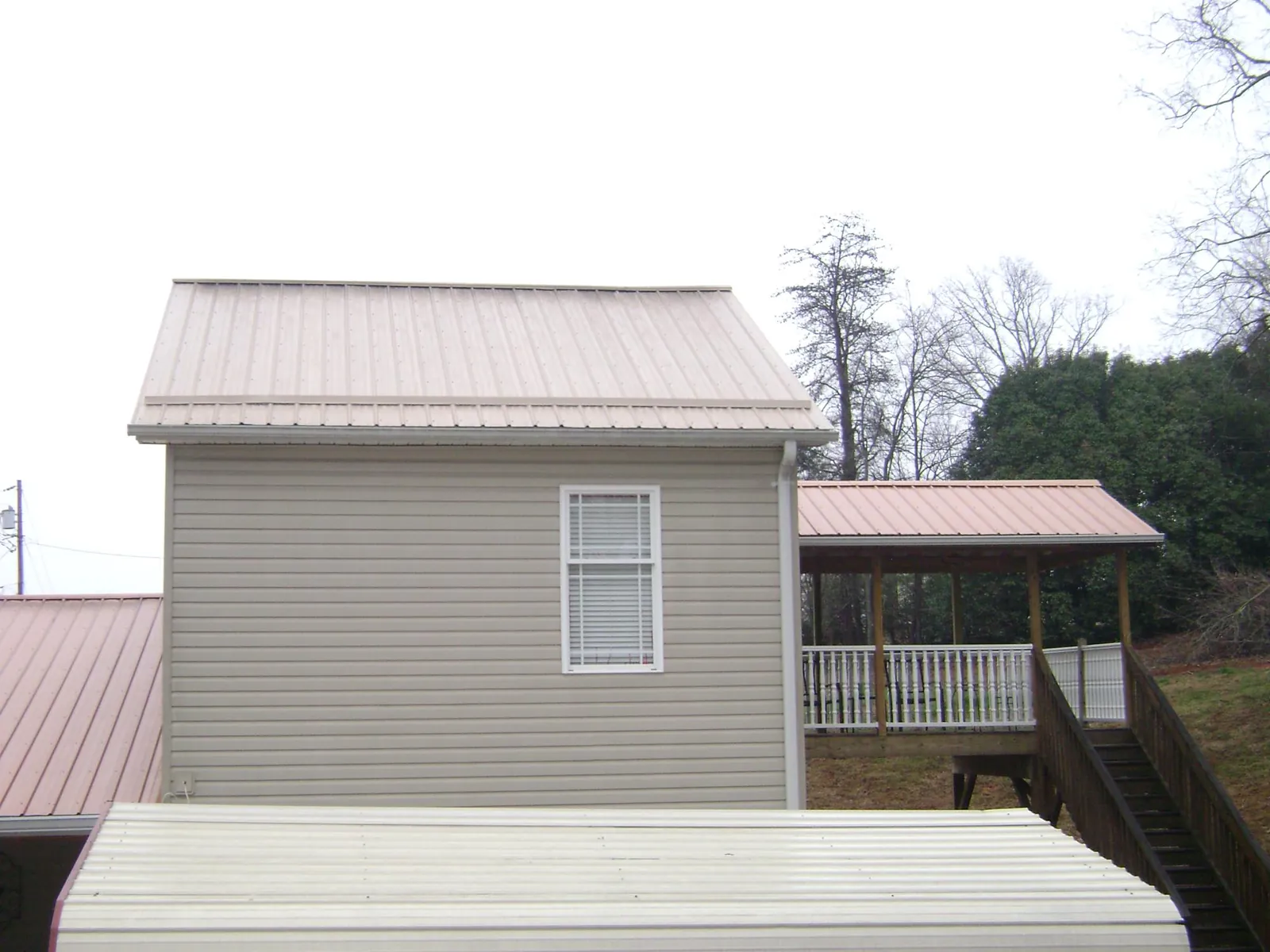 Tan metal roofs on a two story addition and attached porch, from a Roof Replacement job in Hamilton City